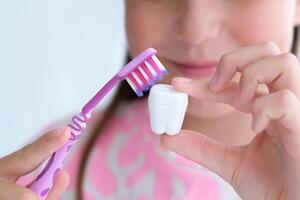 The child holds a plastic milk tooth and a toothbrush in his hands. The concept of brushing and caring for teeth. photo