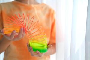 niño jugando naranja y verde ajustado, vistoso flexible para niños juguete, divertido el plastico juguete. adolescente niña obras de teatro seductor foto