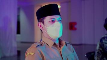 portrait de une en uniforme officier avec une visage masque, permanent à l'intérieur avec une sérieux expression video