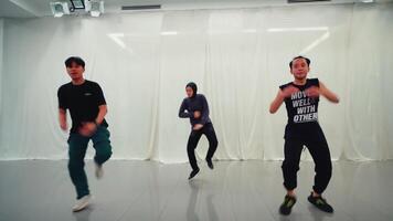 tre persone danza nel un' studio con bianca muri, esprimendo gioia e energia attraverso loro dinamico movimenti. video