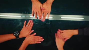 Top view of diverse hands together on a reflective surface, symbolizing teamwork and unity video