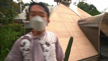 Rear view of a person walking towards a modern, dome-shaped building surrounded by lush greenery, wearing a backpack and a patterned outfit video