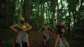 traditionell Tänzer im beschwingt Kostüme und Masken durchführen im ein üppig Grün Wald, präsentieren kulturell Erbe video