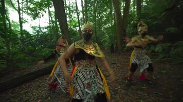 traditionell balinesisch Tänzer im aufwendig Kostüme und Masken durchführen im ein üppig Wald Einstellung, präsentieren kulturell Erbe video