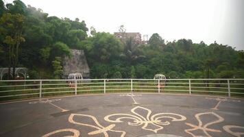 Scenic viewpoint with decorative pavement overlooking lush greenery and a distant building atop a hill video