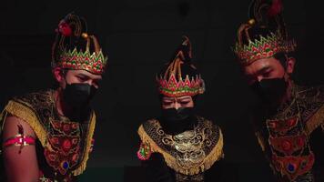 Traditional dancers in ornate costumes and masks, with dramatic lighting casting strong shadows video