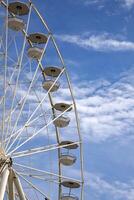 A part of the Ferris wheel against a cloudy blue sky photo