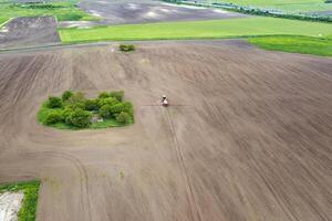 Aerial view of tractor spraying aerosol on a grain fields photo