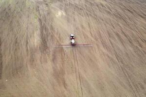 Aerial view of tractor spraying aerosol on a grain fields photo