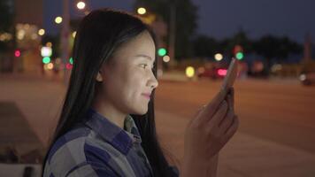 jovem ásia mulher usando inteligente telefone tábua dentro a cidade ruas video