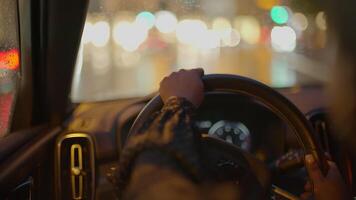 femelle la personne avec noir frisé cheveux conduite voiture dans le ville à nuit circulation video