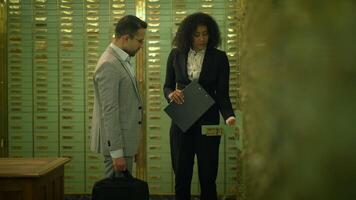 ein Mann und ein Frau im formal tragen sind Stehen im ein Bank Gewölbe video