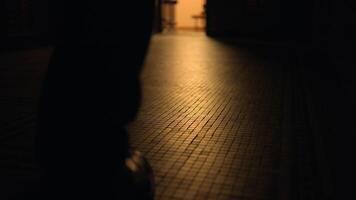 une homme en marchant vers le bas une faible couloir avec une chaud ambre lumière éclairant le bois dur sol video