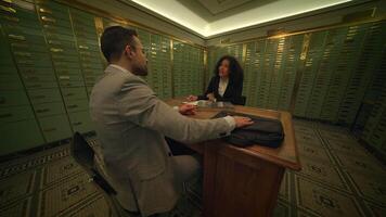 ein Mann und ein Frau sind Teilen ein Tabelle im ein Bank Gebäude video