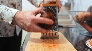 Grating a beetroot in the kitchen, A person grates a beetroot on a wooden cutting board in a kitchen, video