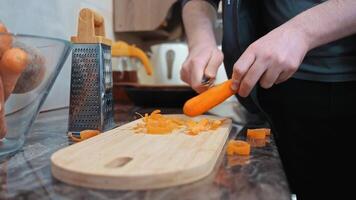 peeling carote nel il cucina, un' persona bucce carote su un' di legno taglio tavola nel un' cucina, sottolineando il preparazione di fresco verdure per cucinando. video