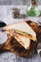 Club sandwich with chicken meat, tomato and lettuce on a board on the table vertical view photo