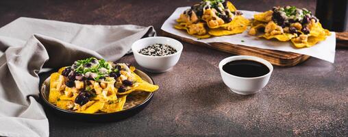 Mexican nacho chips baked with chicken, black beans and cheese on a plate web banner photo