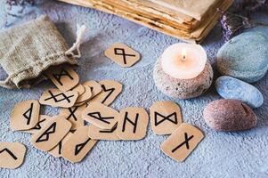 Scandinavian ancient runes for fortune telling, a bag, a candle and stones on the table photo