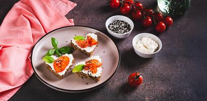 Crostini on rye bread in the shape of a heart with ricotta and tomatoes on a plate web banner photo