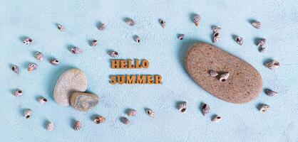 Concept hello summer text, stones and shells on blue background top view web banner photo