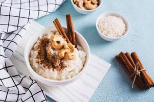 Bowl with delicious rice pudding with cinnamon and nuts on the table photo