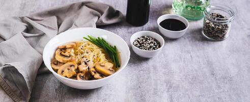 Funchose rice noodles with mushrooms and green onions in a bowl on the table web banner photo