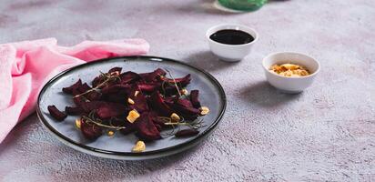 Pieces of baked beets with rosemary and garlic on a plate on the table web banner photo