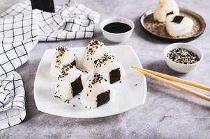 Homemade onigiri rice balls with tuna and nori on a plate on the table photo
