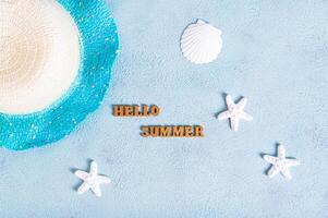 Concept hello summer text, hat and starfish on blue background top view photo