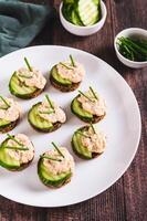 Appetizing sandwiches with pollock caviar, cucumber and herbs on a plate vertical view photo