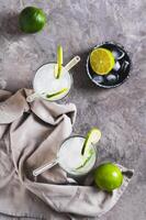 Alcoholic mojito cocktail with lime and ice in glasses on the table top and vertical view photo