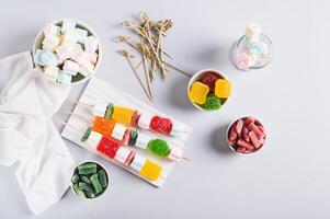 Gummy candy kabobs on skewers served on the table top view photo
