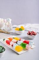 Gummy candy kabobs on skewers served on the table vertical view photo