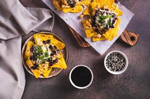 Mexican nacho chips baked with chicken, black beans and cheese on a plate top view photo