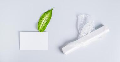 Roll of clean transparent plastic bags, sheet for inscription and fresh leaf on blue background photo