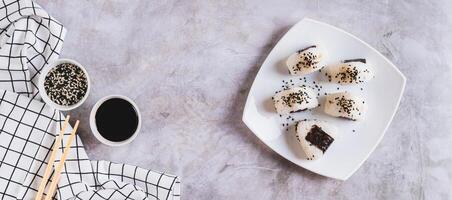 Homemade onigiri rice balls with tuna and nori on a plate on the table top view web banner photo