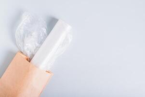 Roll of blank plastic bags in paper bag on blue background top view photo