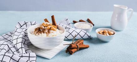 Rice pudding with cinnamon and cashews in a bowl on the table web banner photo