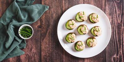 Appetizing sandwiches with pollock caviar, cucumber and herbs on a plate top view web banner photo