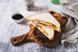 Club sandwich with chicken meat, tomato and lettuce on a board on the table photo