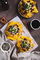 Mexican baked nachos with chicken, black beans and cheese on a board top and vertical view photo