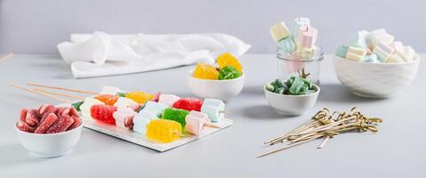 Gummy candy kabobs on skewers served on the table web banner photo