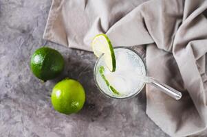 Close up of refreshing summer mojito cocktail with ice and lime in a glass on the table top view photo
