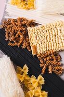 Close up of funchoza, udon, black noodles, buckwheat and wheat pasta on a napkin vertical view photo