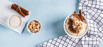 Bowl with delicious rice pudding with cinnamon and nuts on the table top view web banner photo