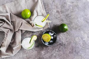 Refreshing summer mojito cocktail with ice and lime in glasses on the table top view photo