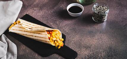 Mexican Burrito with corn, chicken and peppers in a tortilla on a slate board web banner photo