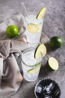 Alcoholic mojito cocktail with lime and ice in glasses on the table vertical view photo