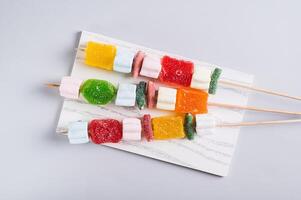 Close up of Gummy candy kabobs on skewers served on the table top view photo